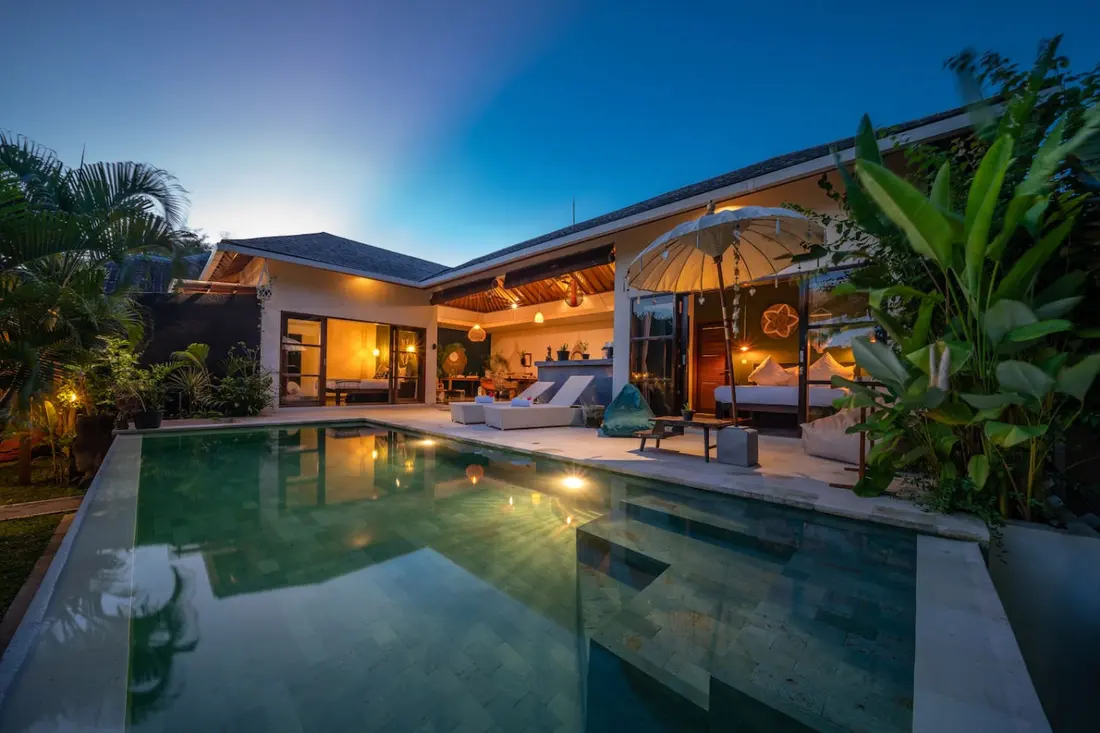Karma House illuminated at dusk beside its private swimming pool