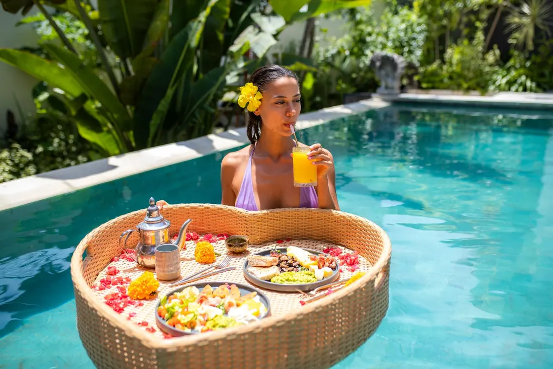 A guest enjoying a floating breakfast in the pool at Tropical Bungalow